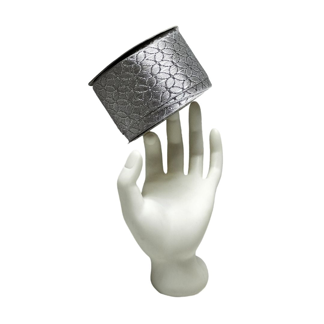 Silver textured container on a white mannequin hand against a white background